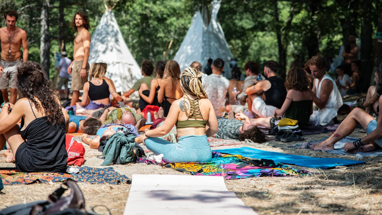 People seated in a circle at an outdoor retreat with tipis behind them