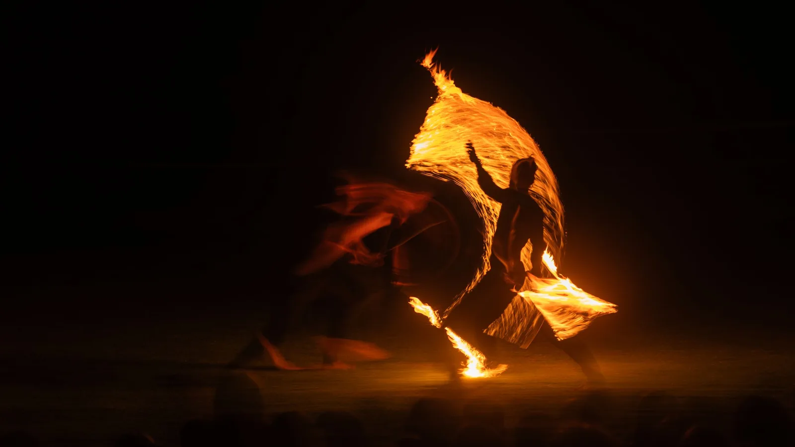 A fire dancer spinning flames in the dark
