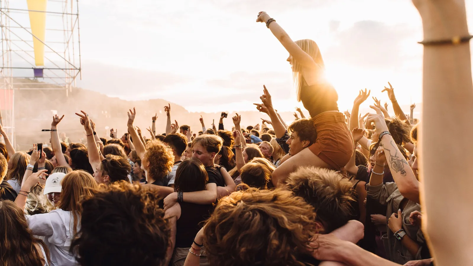 A festival crowd at golden hour with hands in the air