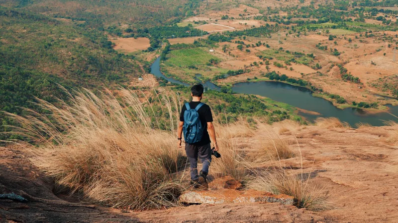 A hiker on a hillside looking down over a lake in a wooded valley