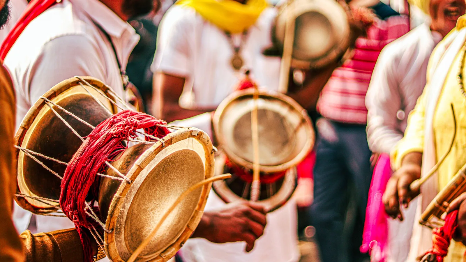 Drummers in bright colours playing large drums at an outdoor festival