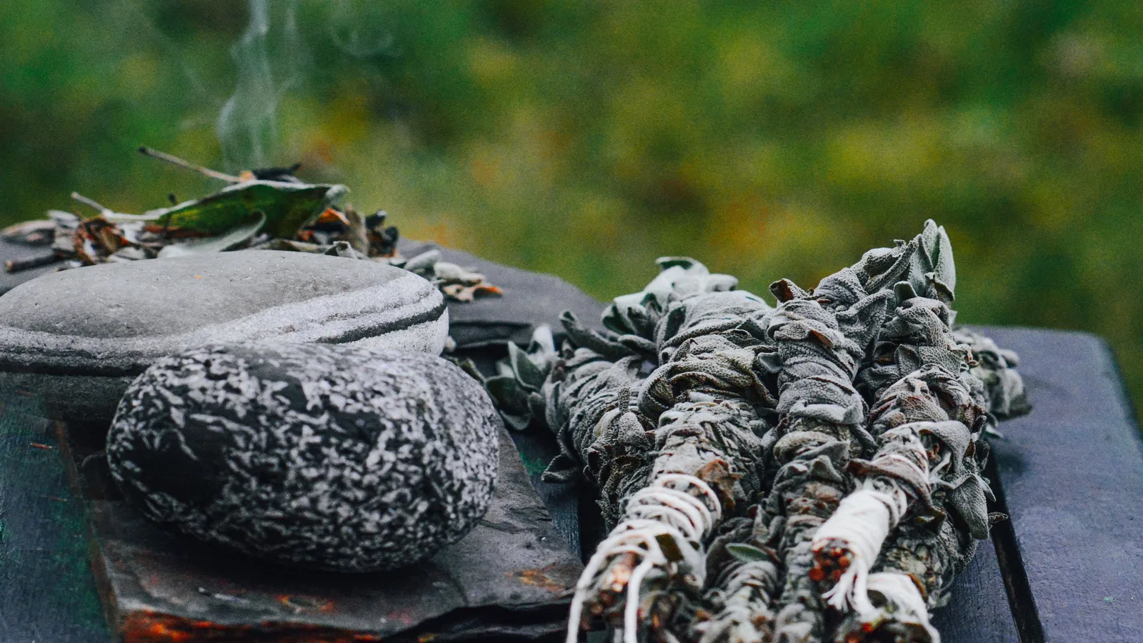 Bundles of dried sage smouldering on stones outdoors